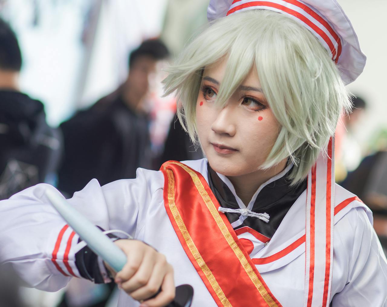 An Asian woman in costume poses during a cosplay parade outdoors, showcasing intricate details.