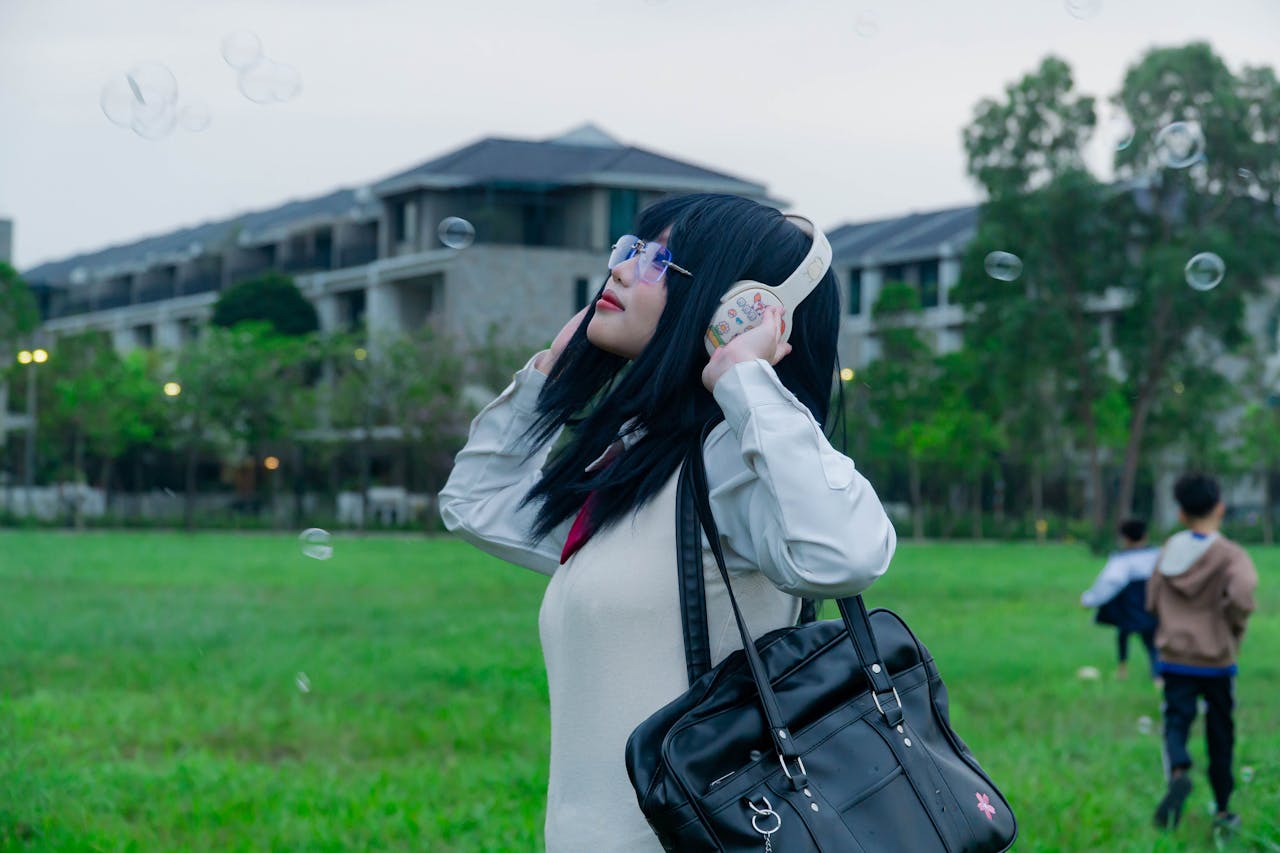 Young woman with headphones enjoying music outdoors, surrounded by bubbles and greenery.