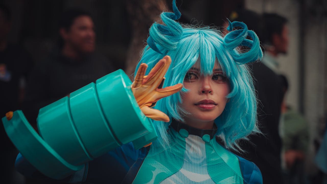 About Cosplayer in blue wig and costume striking a pose at an outdoor event.