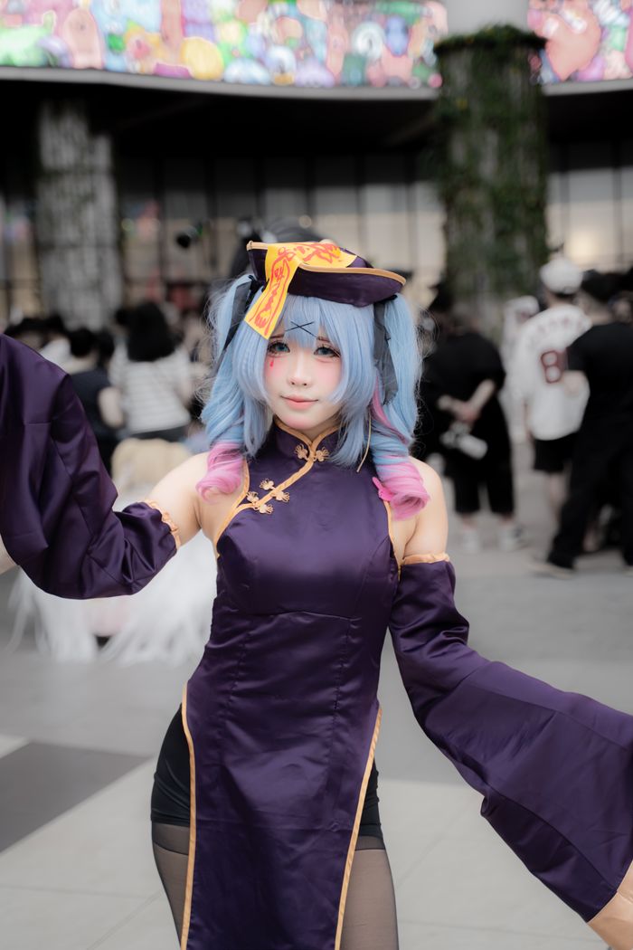 Menus Cosplayer in colorful attire poses at lively outdoor event with crowd.